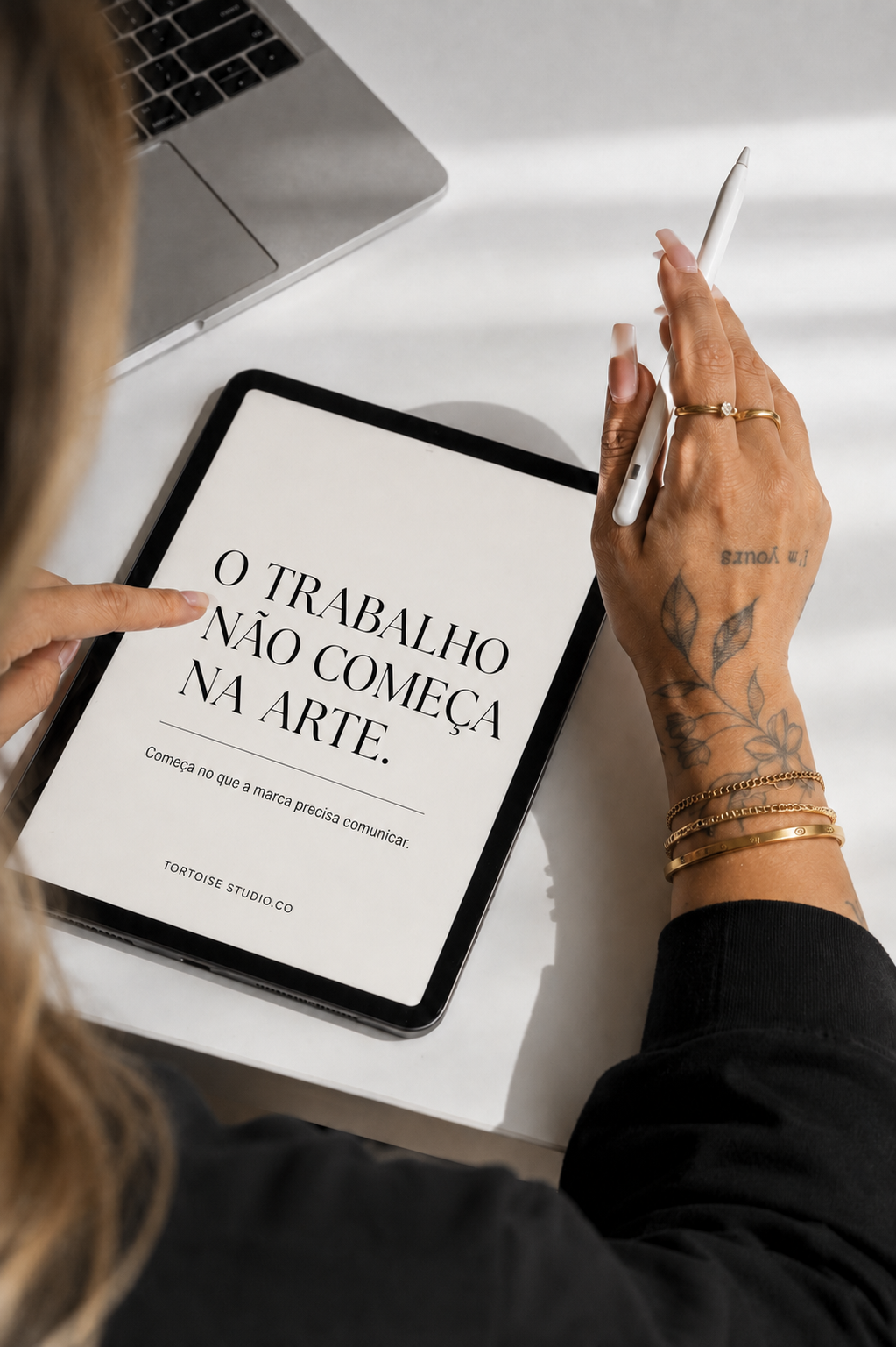 Detalhe das mãos trabalhando em um iPad com o manifesto do estúdio